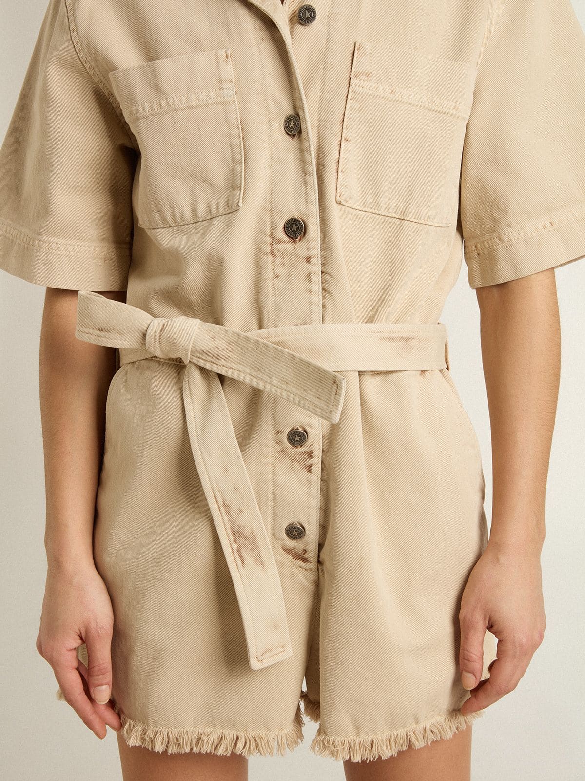 Women's romper in beige denim with belt and frayed hem