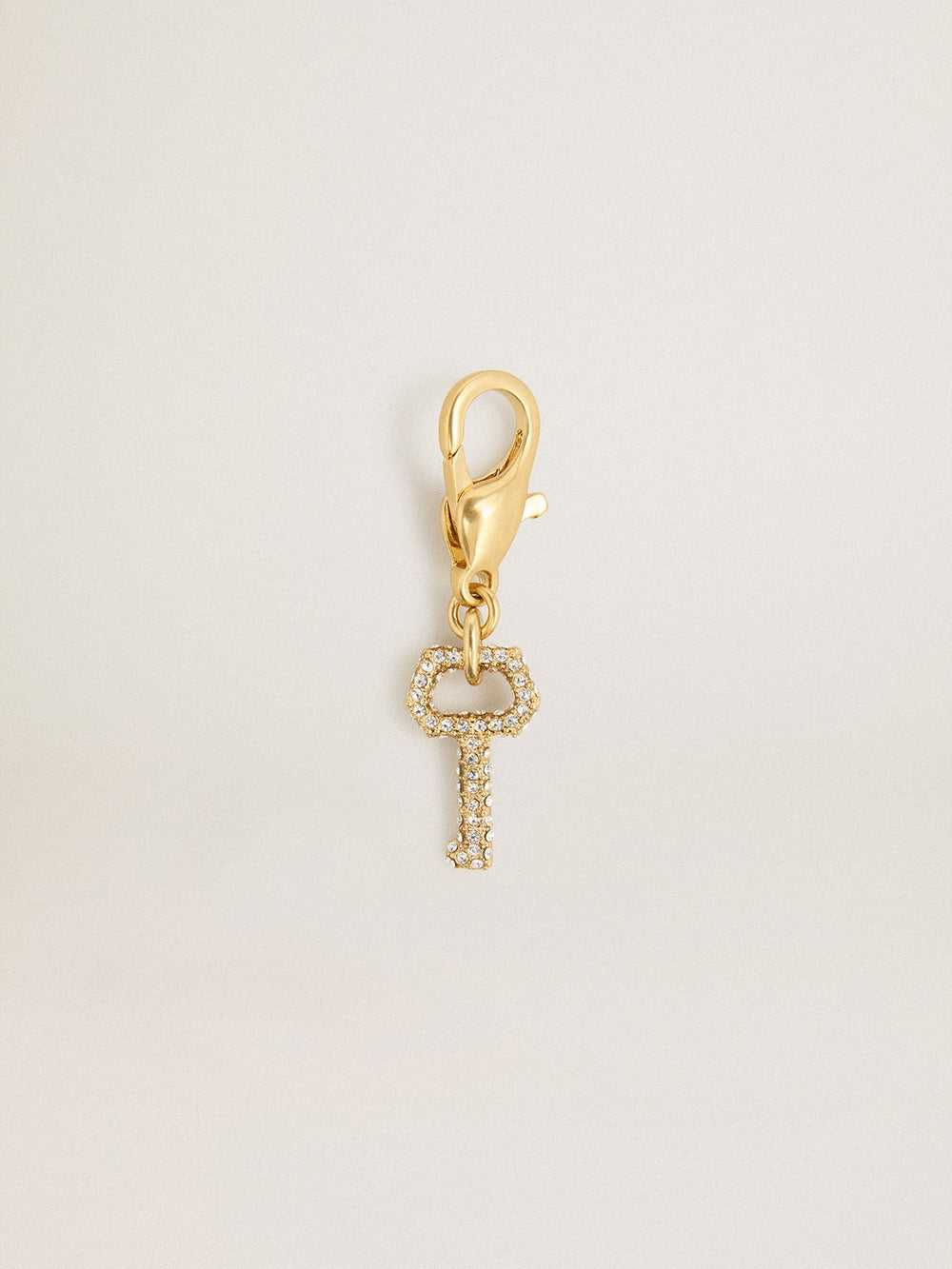 Key-shaped charm in gold-colored brass with crystals