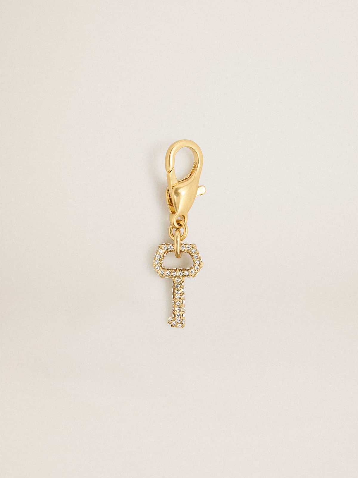Key-shaped charm in gold-colored brass with crystals