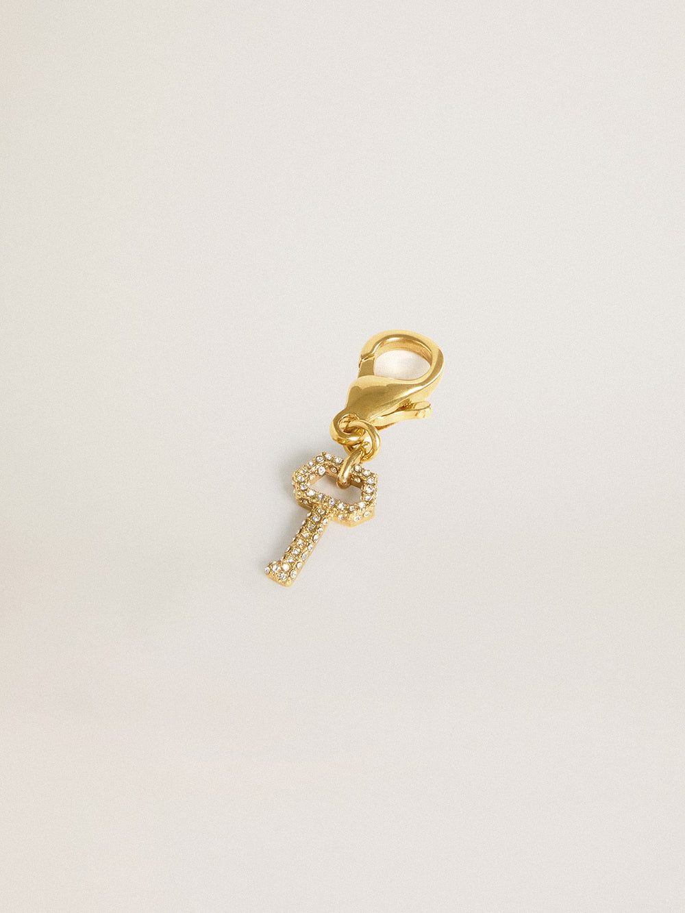 Key-shaped charm in gold-colored brass with crystals