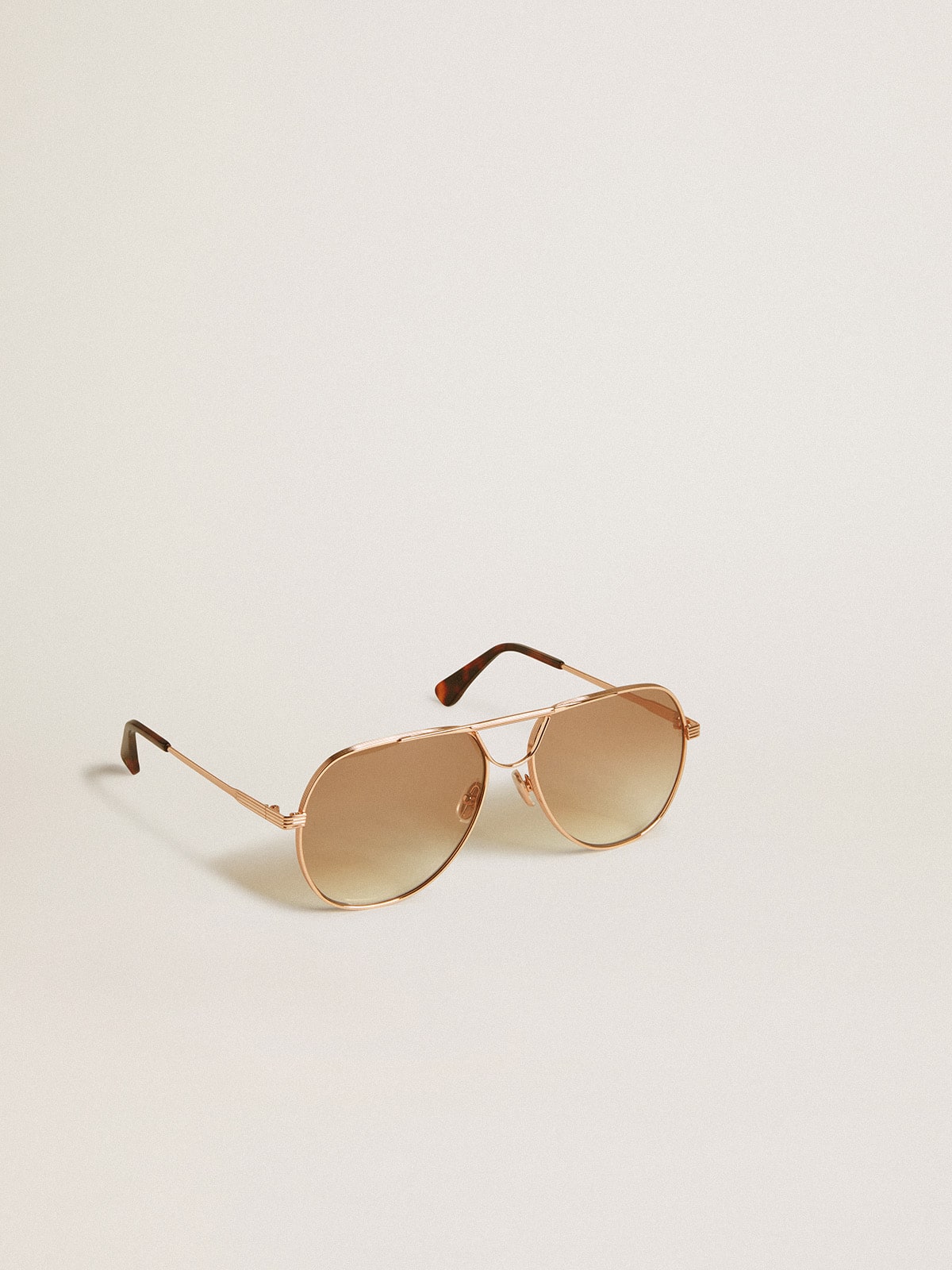 Aviator style sunglasses with rose-gold frame and honey-colored lenses