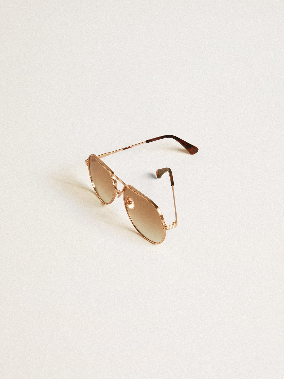 Aviator style sunglasses with rose-gold frame and honey-colored lenses